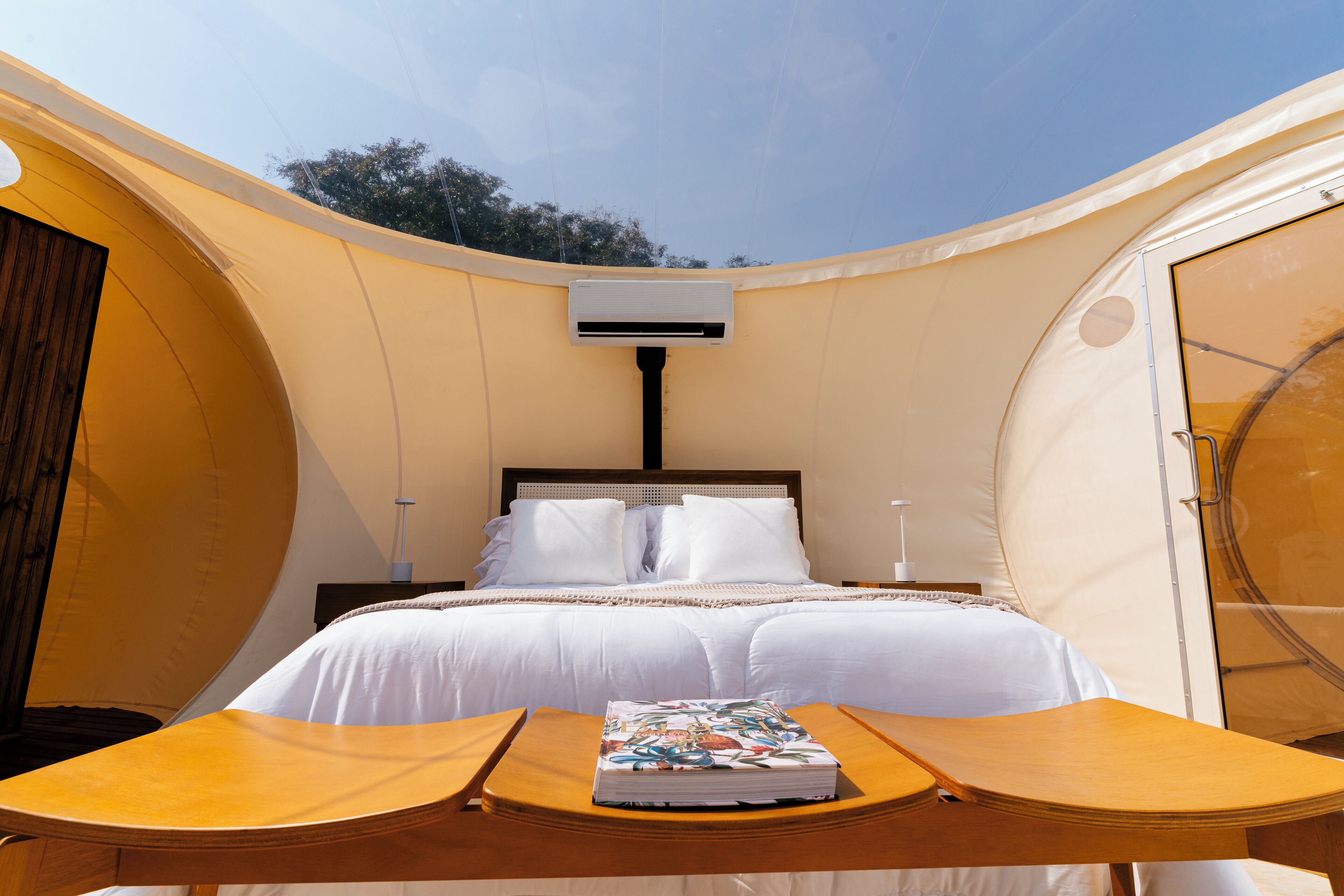 A tent-style room with a bed, a table, and a book.