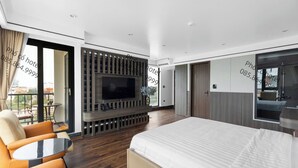 A modern hotel room with a large bed, a TV mounted on the wall, a seating area with a table, and a balcony with a view. - Pho Co Hotel Ninh Binh (Ninh Binh)