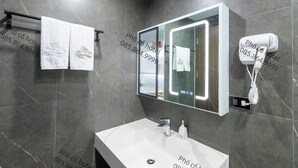 A modern bathroom with a large mirror, a hairdryer, and a towel rack. - Pho Co Hotel Ninh Binh (Ninh Binh)