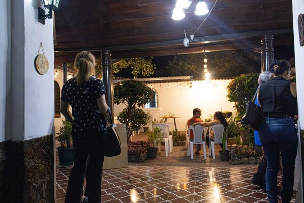 Un espace extérieur aménagé en terrasse, avec un sol carrelé, des chaises blanches et des plantes en pot.