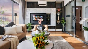 A modern living room with a sofa, a coffee table with sunflowers, a fireplace, and a TV mounted on the wall. - Crescendo Unique Studio (Hanoi)