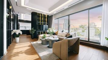 A modern living room with a sofa, coffee table, and a view of the city skyline through large windows.