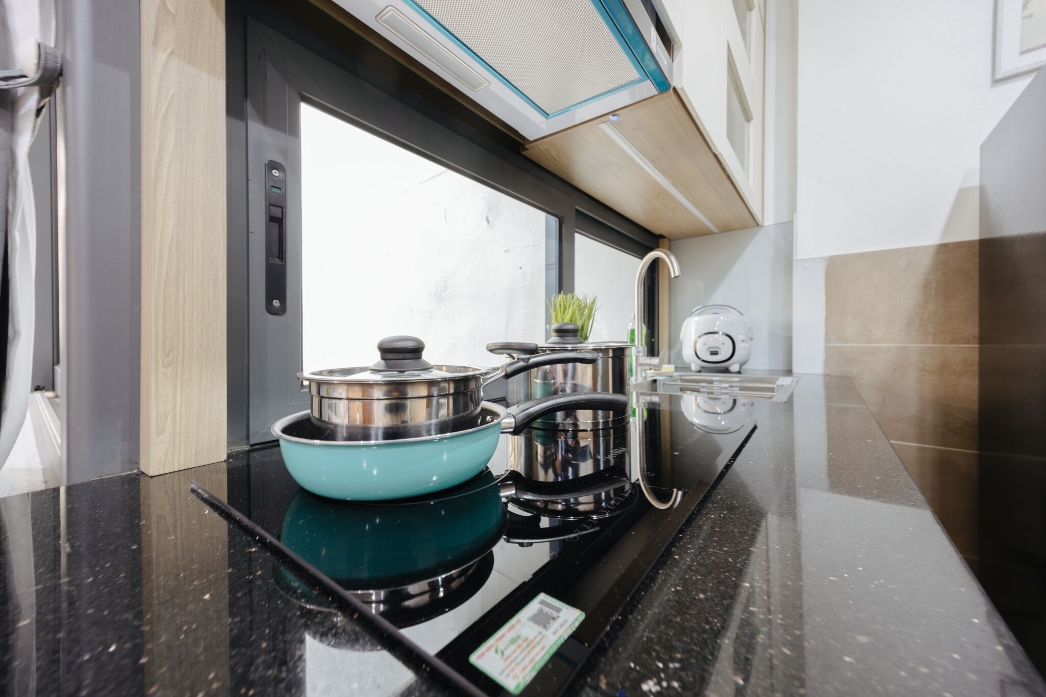 Una cocina moderna con encimera negra, utensilios de cocina de acero inoxidable y un ventanal que proporciona luz natural.
