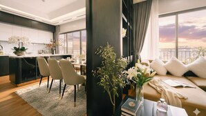 A modern living room with a sofa, a dining table, and chairs. There is a large window with a view of the city skyline. - Crescendo Unique Studio (Hanoi)
