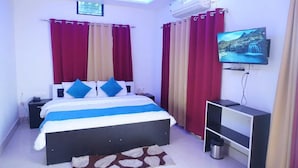 Une chambre à coucher avec un lit, des rideaux, un téléviseur et un ventilateur de plafond.