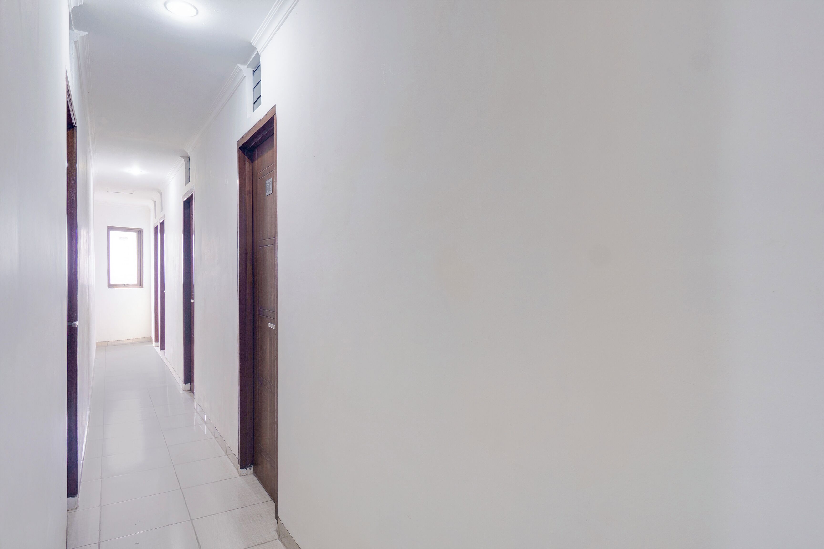 A long, narrow hallway with white walls and a tiled floor.