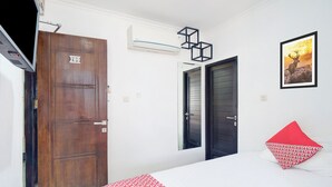 A hotel room with a wooden door labeled 209, a bed with a white and red patterned bedspread, and a framed picture of a deer on the wall. - Townhouse Oak Ancol (Jakarta)