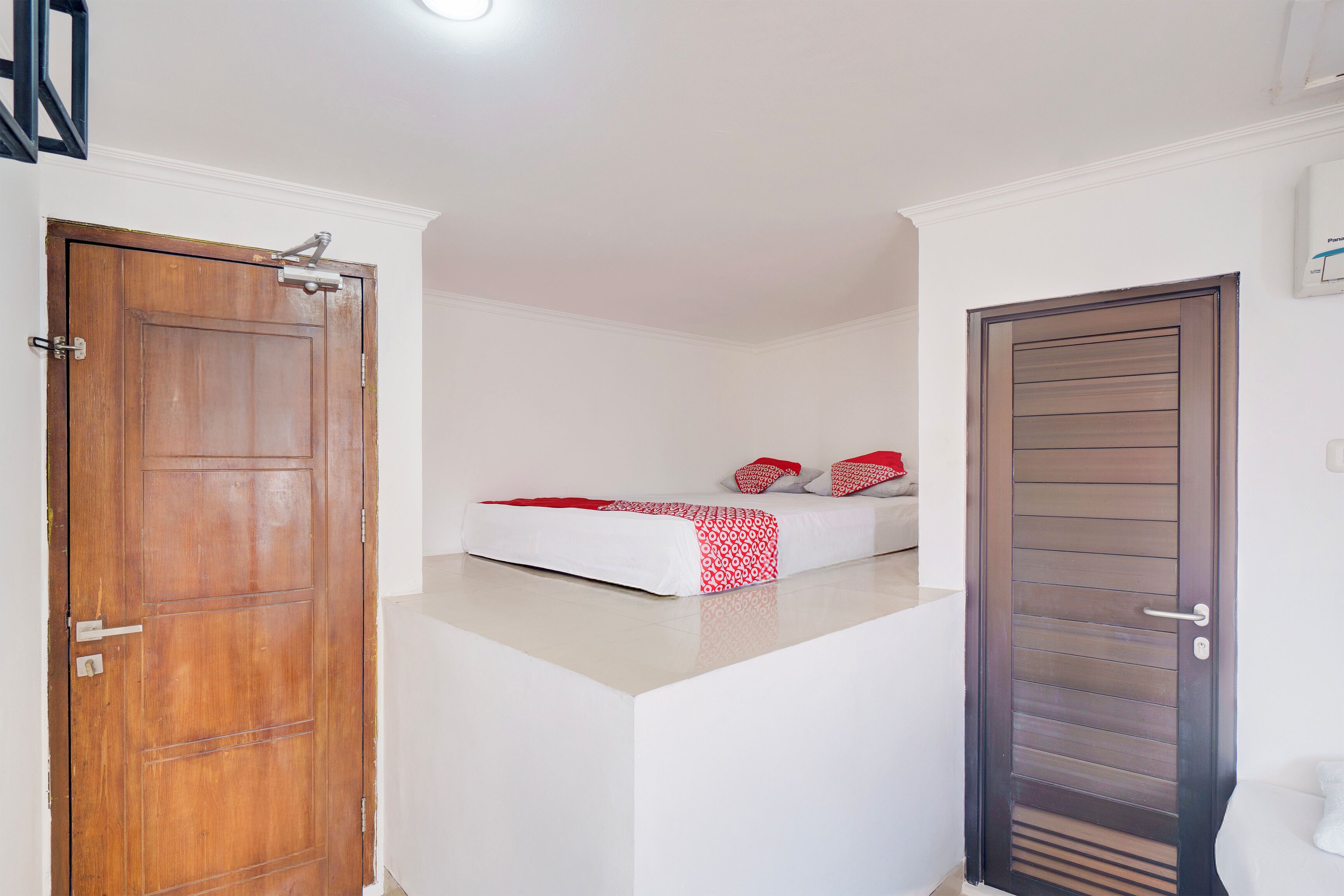 A bedroom with a bed, a wooden door, and a white wall.