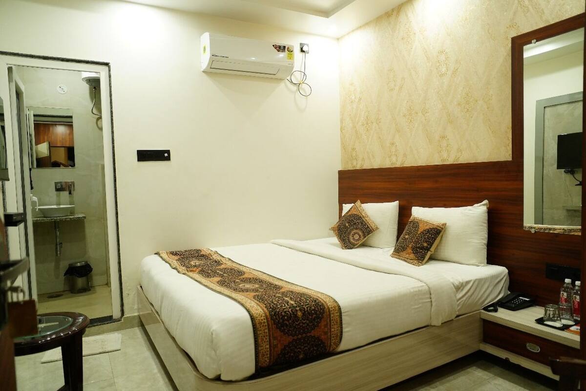 A hotel room with a bed, bedside table, and a mirror.