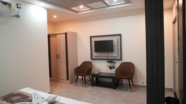 Une chambre d’hôtel comprenant un lit, un bureau avec deux chaises, une télévision et une armoire.