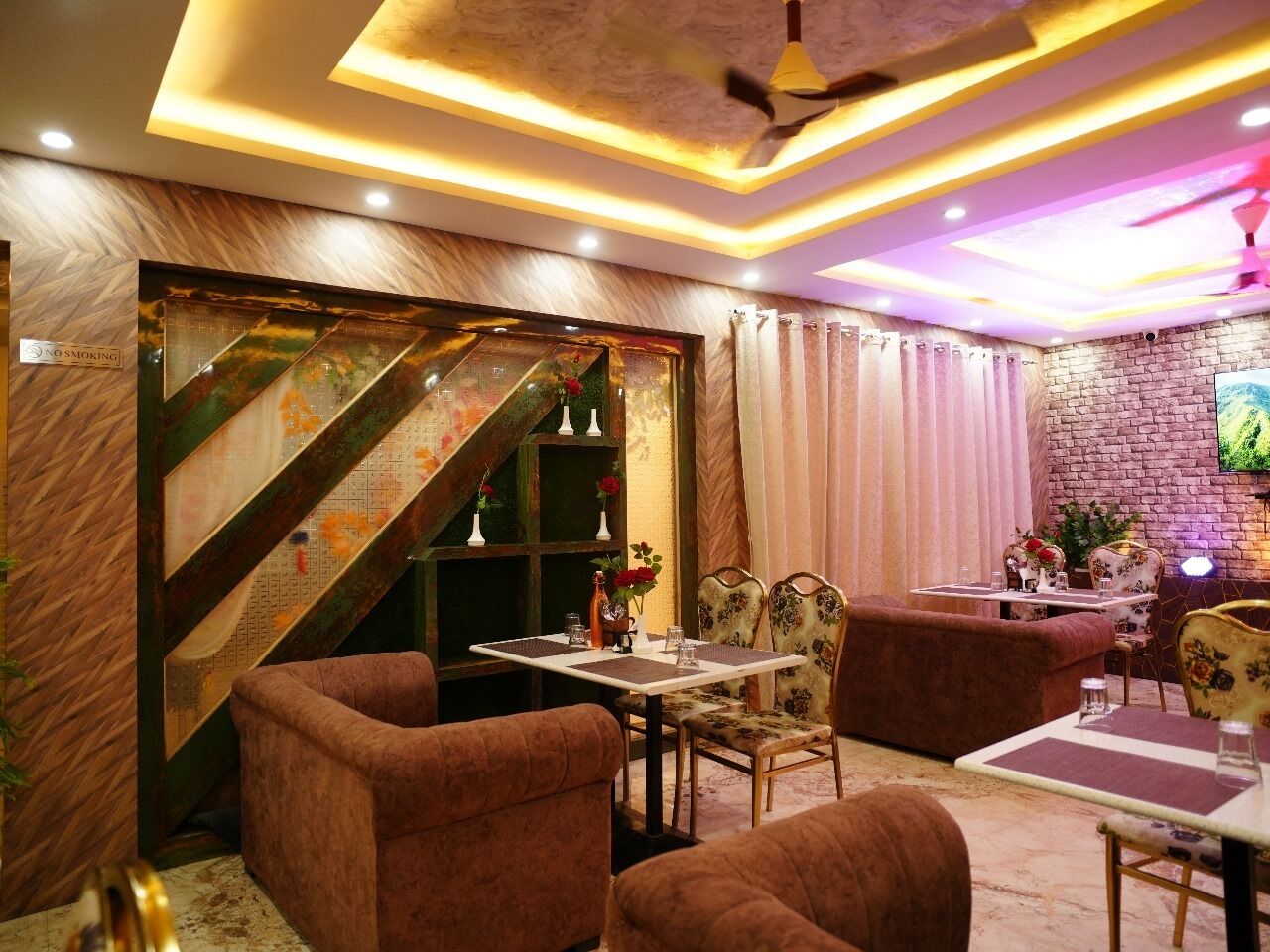 A cozy dining area with a staircase, cushioned seating, and a flat-screen TV mounted on the wall.