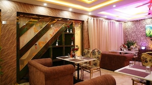 A cozy dining area with a staircase, cushioned seating, and a flat-screen TV mounted on the wall. - Hotel Banaras Palace (Varanasi)