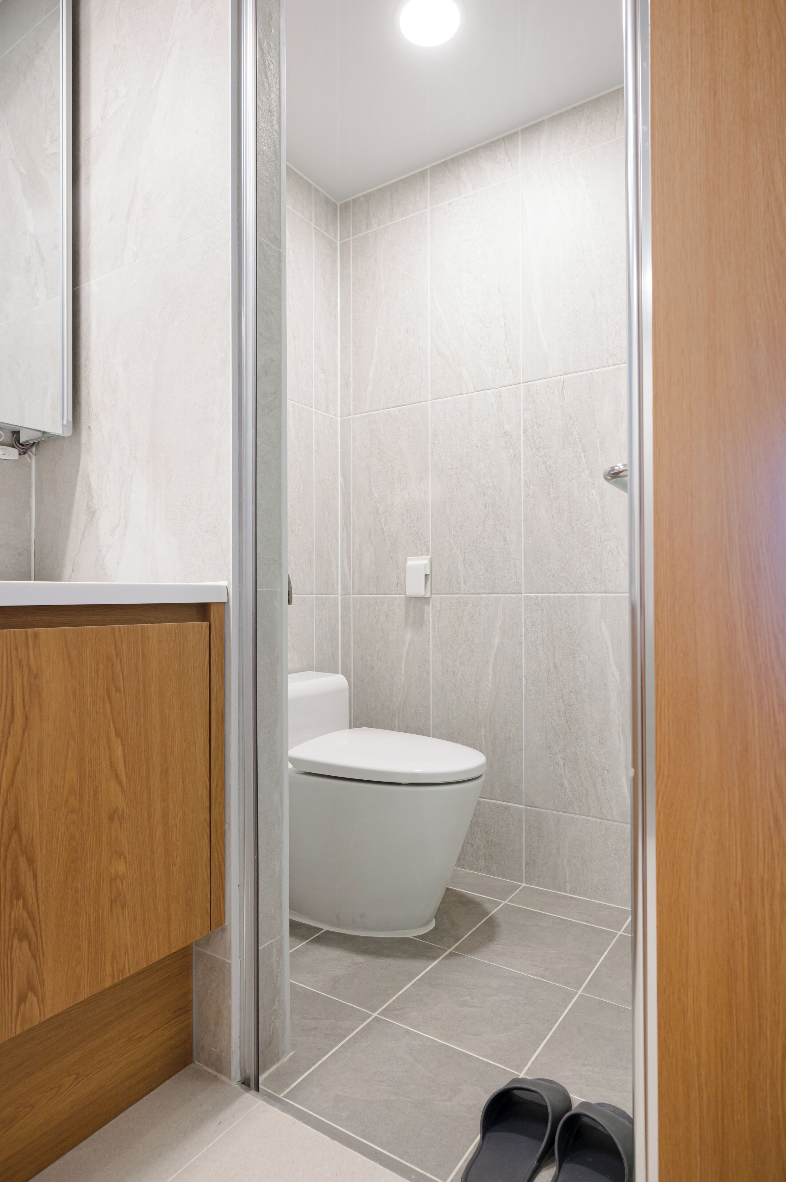 A modern bathroom with a toilet, shower, and wooden vanity.