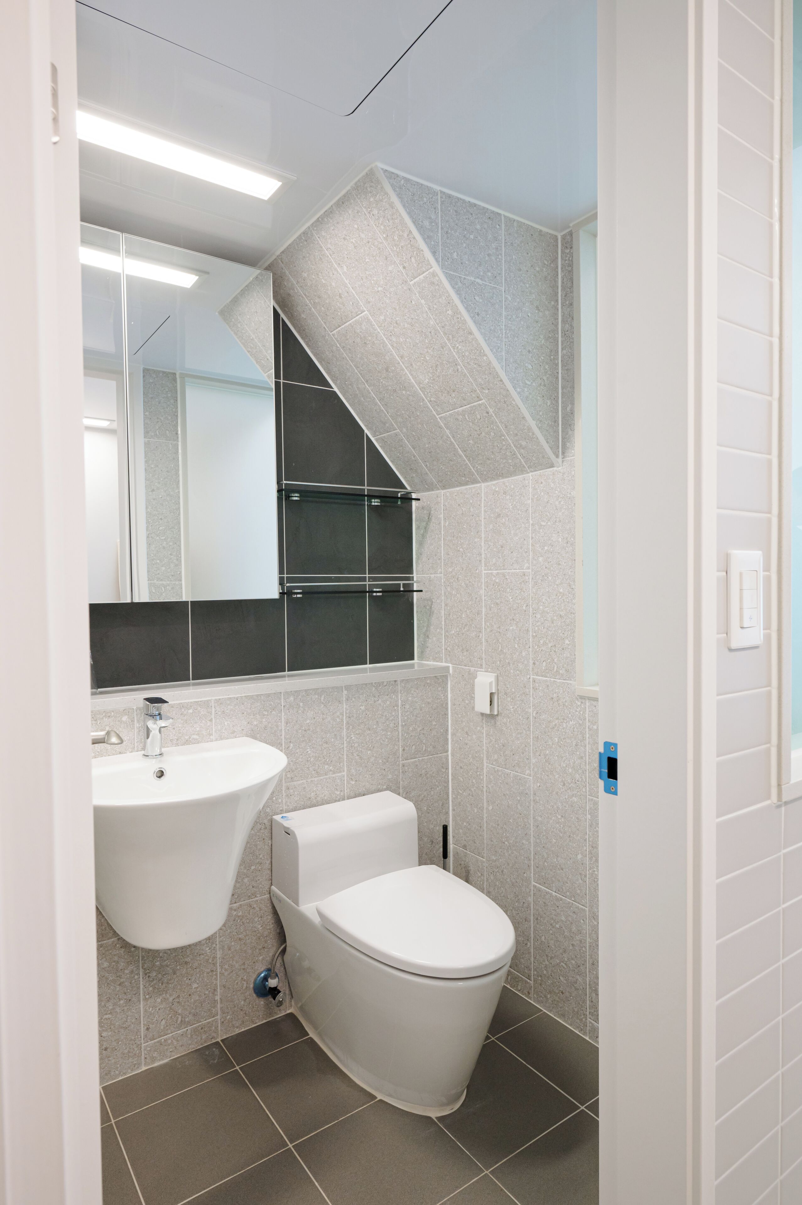 Un baño moderno con un lavabo blanco, inodoro y espejo sobre el lavabo.