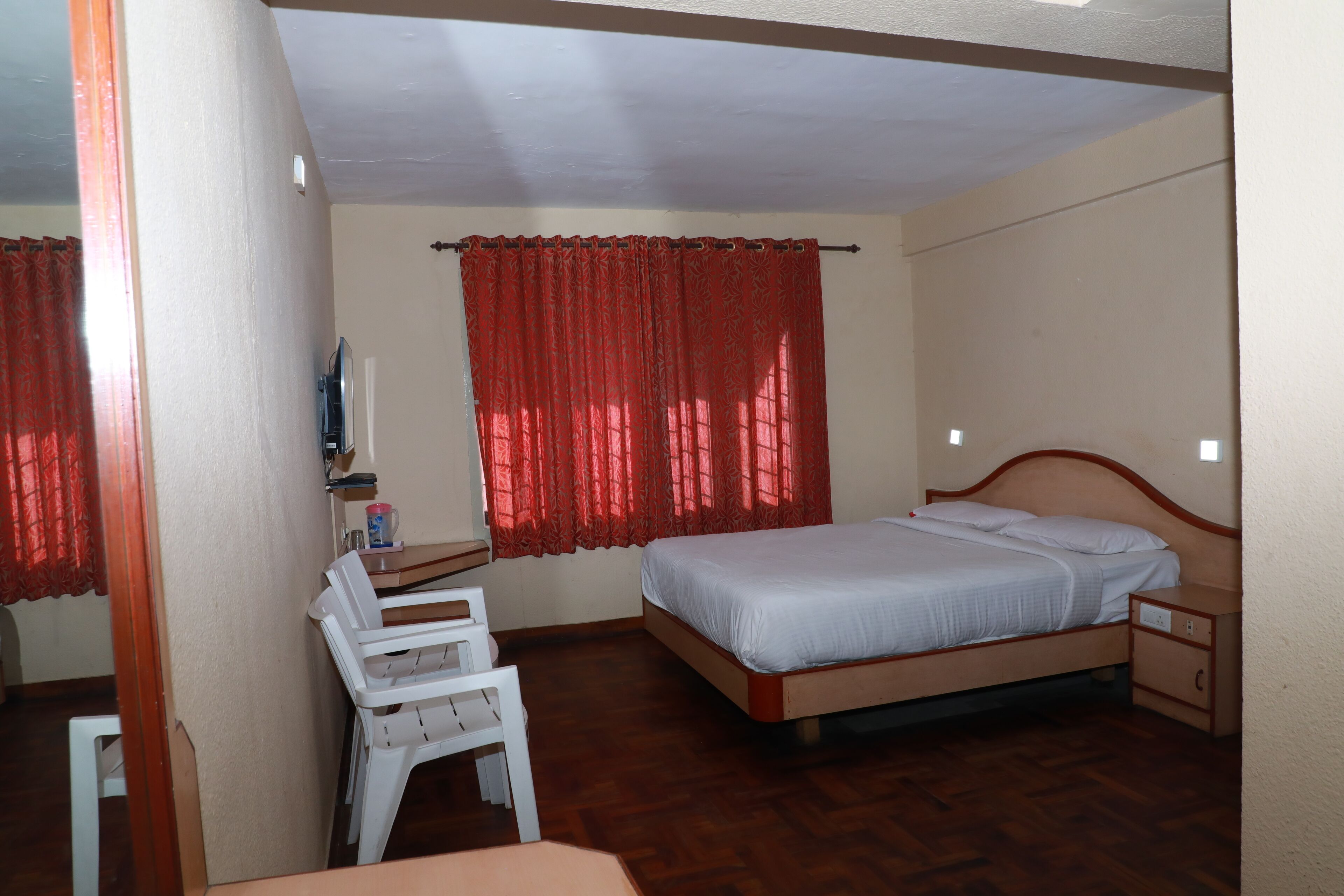 A bedroom with a bed, a desk, a chair, and a nightstand.