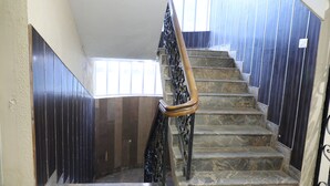 A staircase with stone steps and a wooden handrail, flanked by dark wooden panels and a metal railing. - Royal Hotels, Kodaikanal (Kodaikanal)