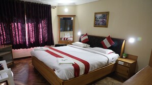 A neatly made bed with white and red linens, a wooden headboard, a bedside table with a plant, and a mirror above the bed. - Royal Hotels, Kodaikanal (Kodaikanal)