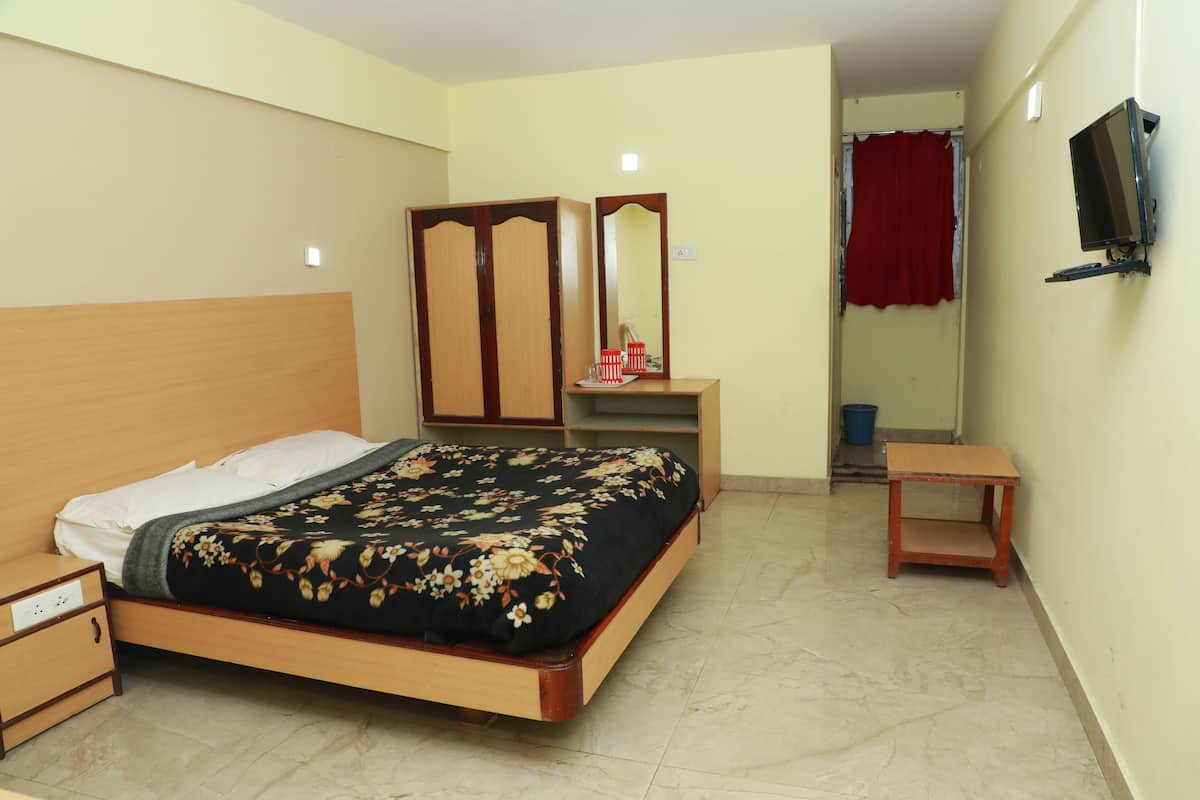 A bedroom with a bed, a nightstand, a dresser, a mirror, a television, and a red curtain.