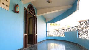 A corridor with a blue wall, a door, and a balcony with a metal railing. - Royal Hotels, Kodaikanal (Kodaikanal)
