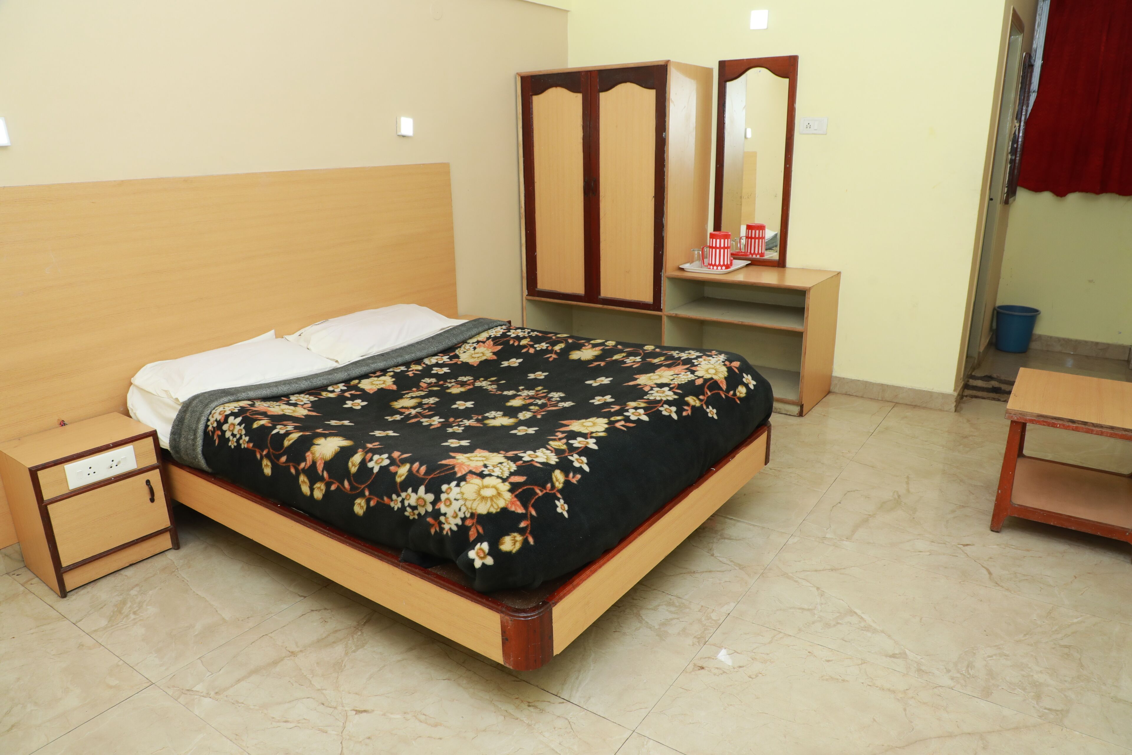 Un dormitorio ordenado con cama, mesita de noche, armario y espejo.