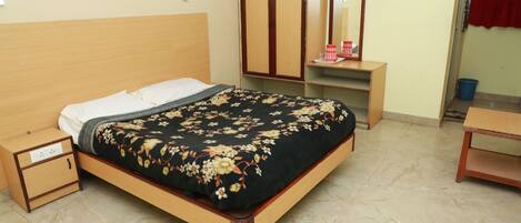 Un dormitorio ordenado con cama, mesita de noche, armario y espejo.