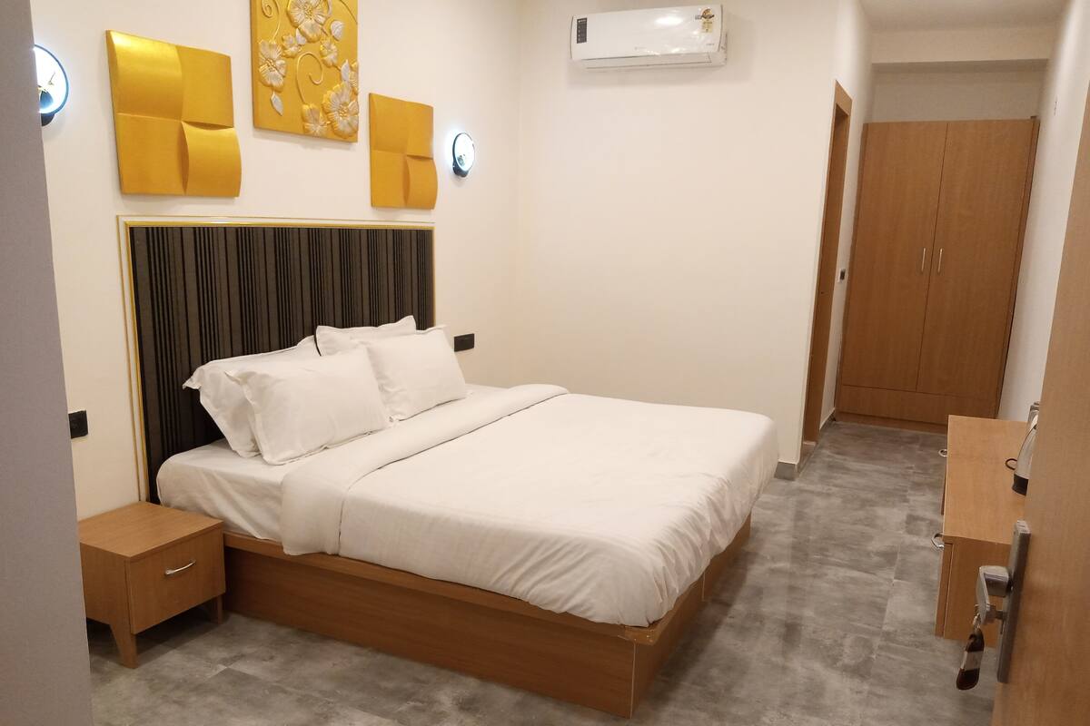 A neatly arranged bedroom with a bed, bedside tables, a wardrobe, and an air conditioning unit.