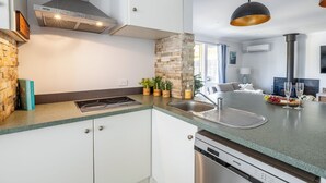 Une cuisine moderne dotée d’une cuisinière intégrée, d’un évier et d’un mur d’accent en pierre.