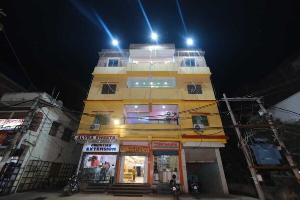 A multi-story building with various shops on the ground floor, including a sweets shop and a furniture store. - Kamala Hotel (Deoghar)