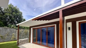 Ein modernes Haus mit Terrasse, Steinmauer und Blick zum Himmel.