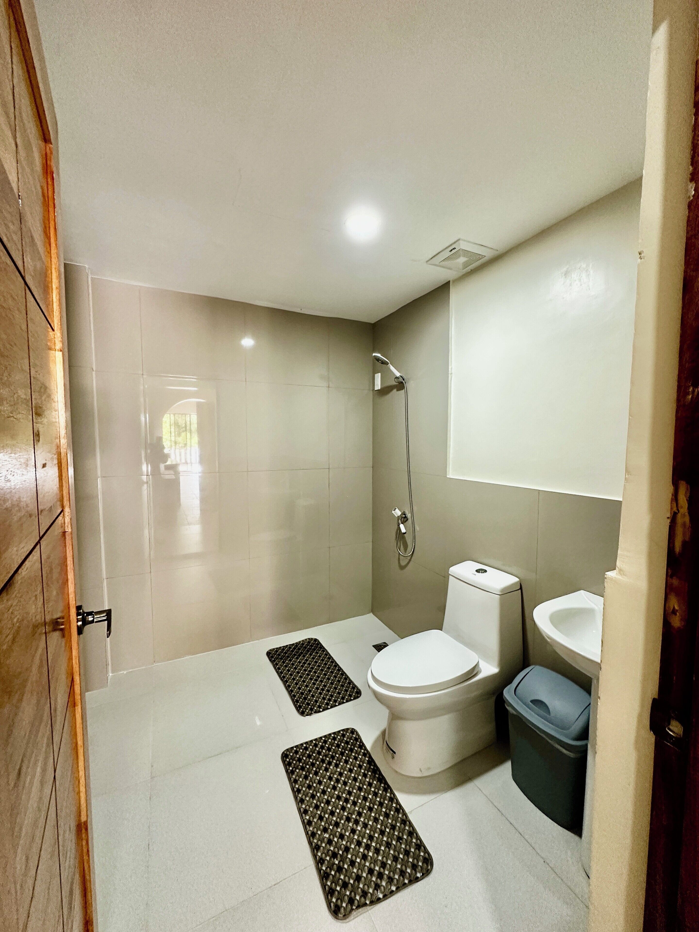 Une petite salle de bain avec des toilettes, un bidet et une douche. Il y a deux tapis sur le sol.