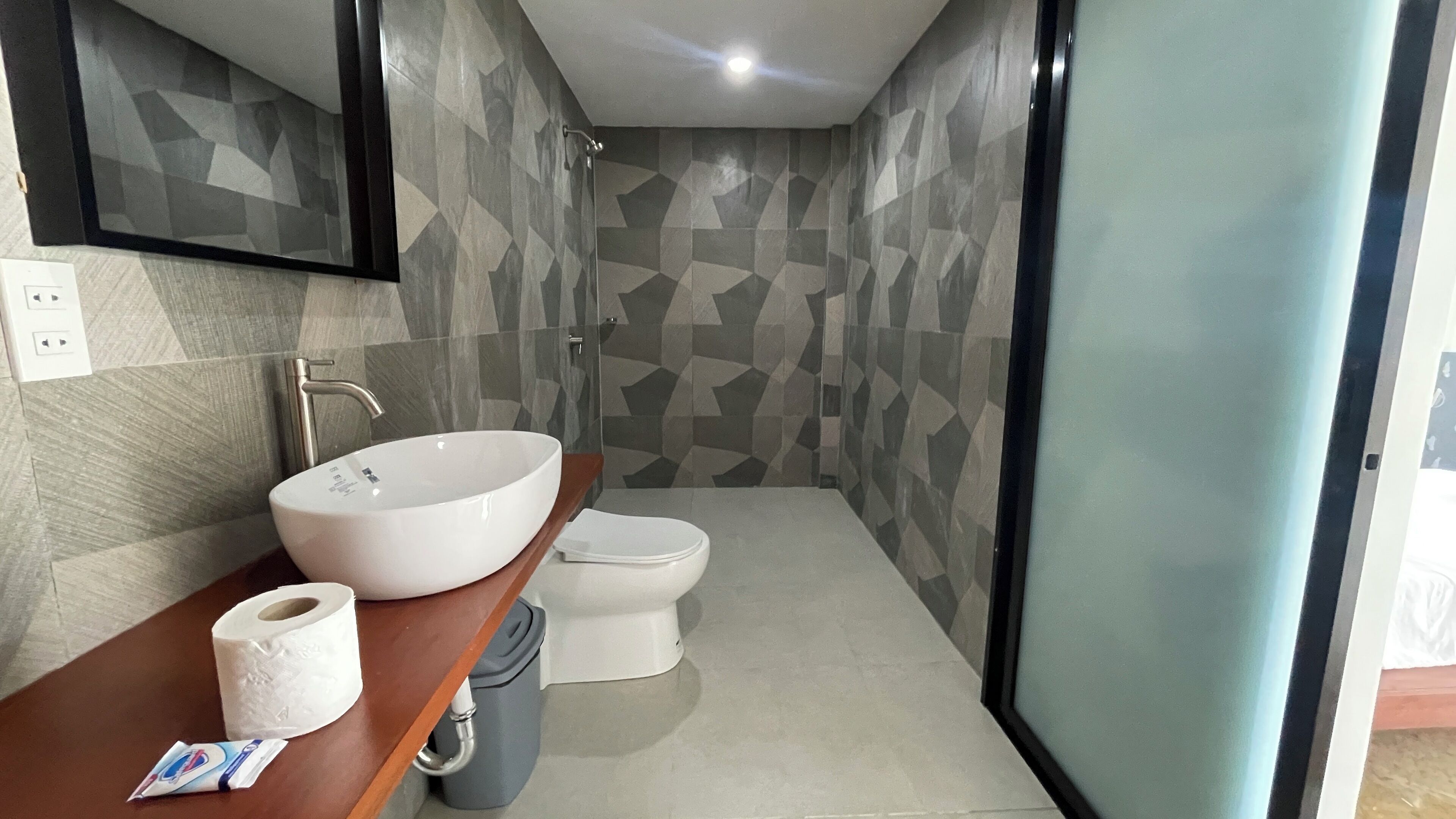 A modern bathroom with a large vessel sink, toilet, and a mirror above the sink.