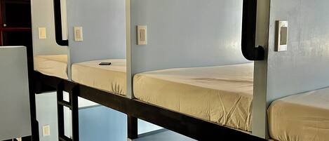 A bunk bed room with a wooden ceiling and light blue walls.