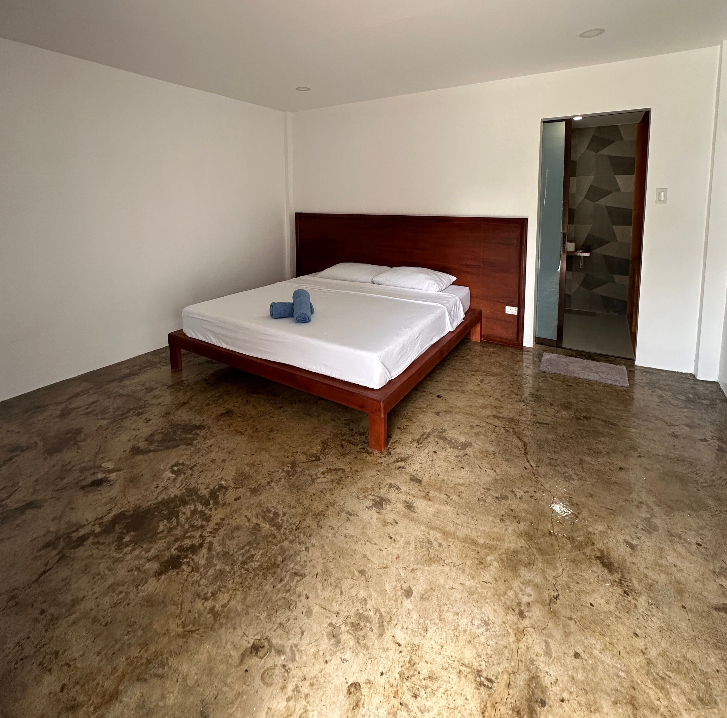 A bedroom with a wooden bed, white linens, and a blue towel.