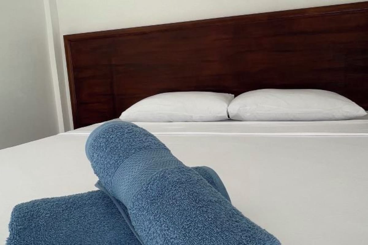 Un lit bien fait, avec des draps blancs et une couverture bleue.