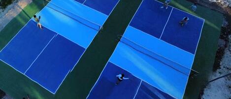 Una cancha de tenis exterior con cuatro canchas.