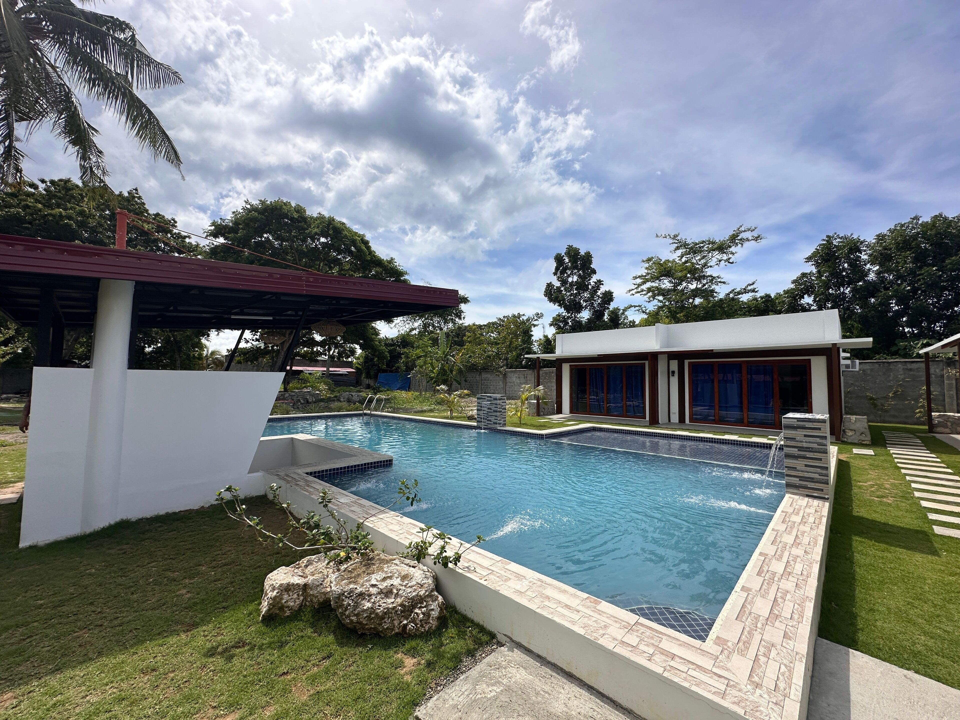 A swimming pool with a modern house and a covered area.