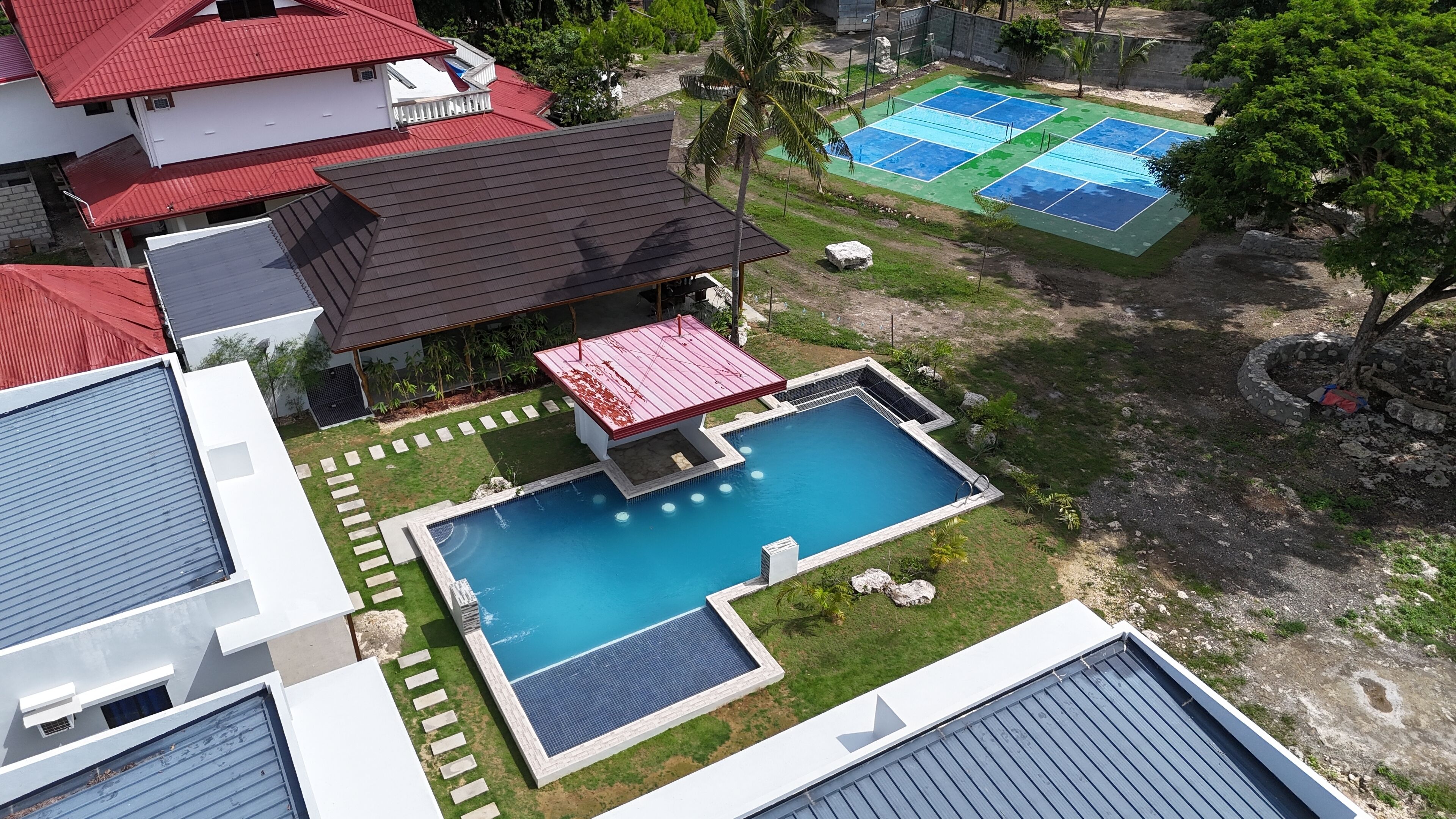 A residential area with a swimming pool, a tennis court, and a gazebo.
