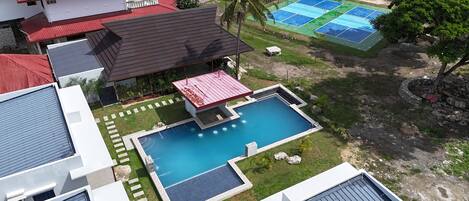 A residential area with a swimming pool, a tennis court, and a gazebo.