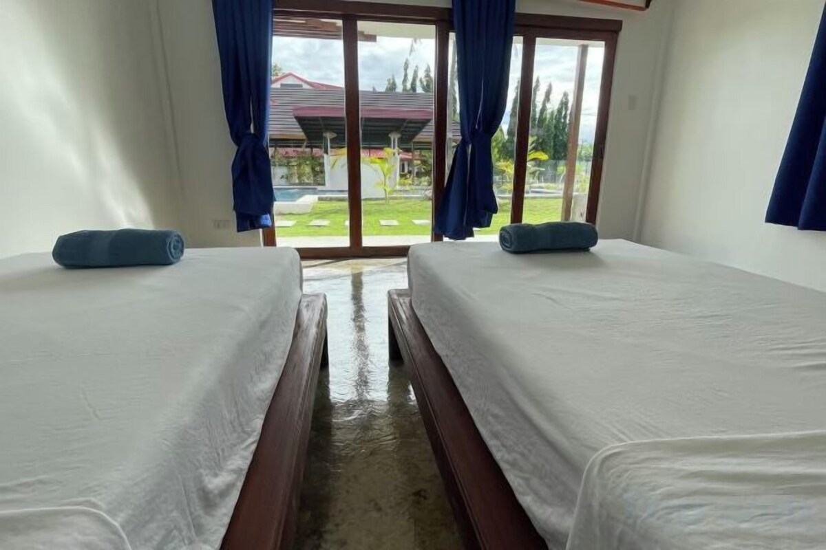 Habitación con dos camas, vista por una puerta de cristal y suelo mojado.