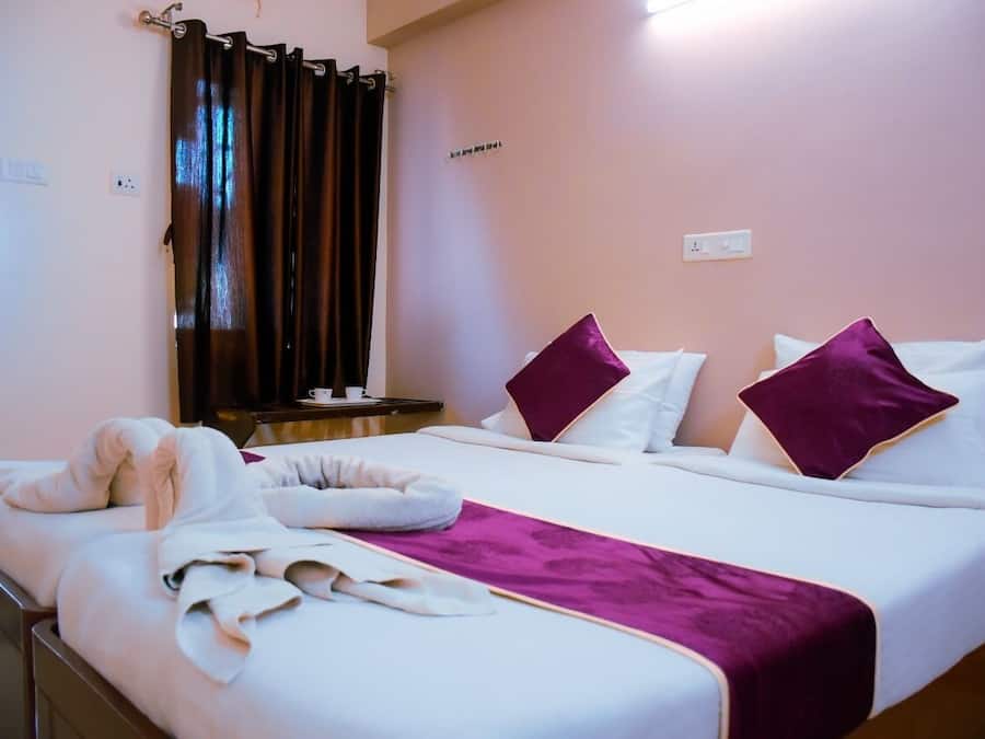 Una habitación de hotel con una cama, una mesita de noche, un espejo y una ventana con cortinas.