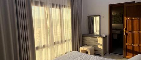 Une chambre à coucher avec un lit, une commode, un miroir et un ventilateur de plafond.