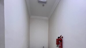 Un pasillo estrecho con un pequeño rincón de cocina equipado con un lavabo y armarios. Un extintor está colgado en la pared.