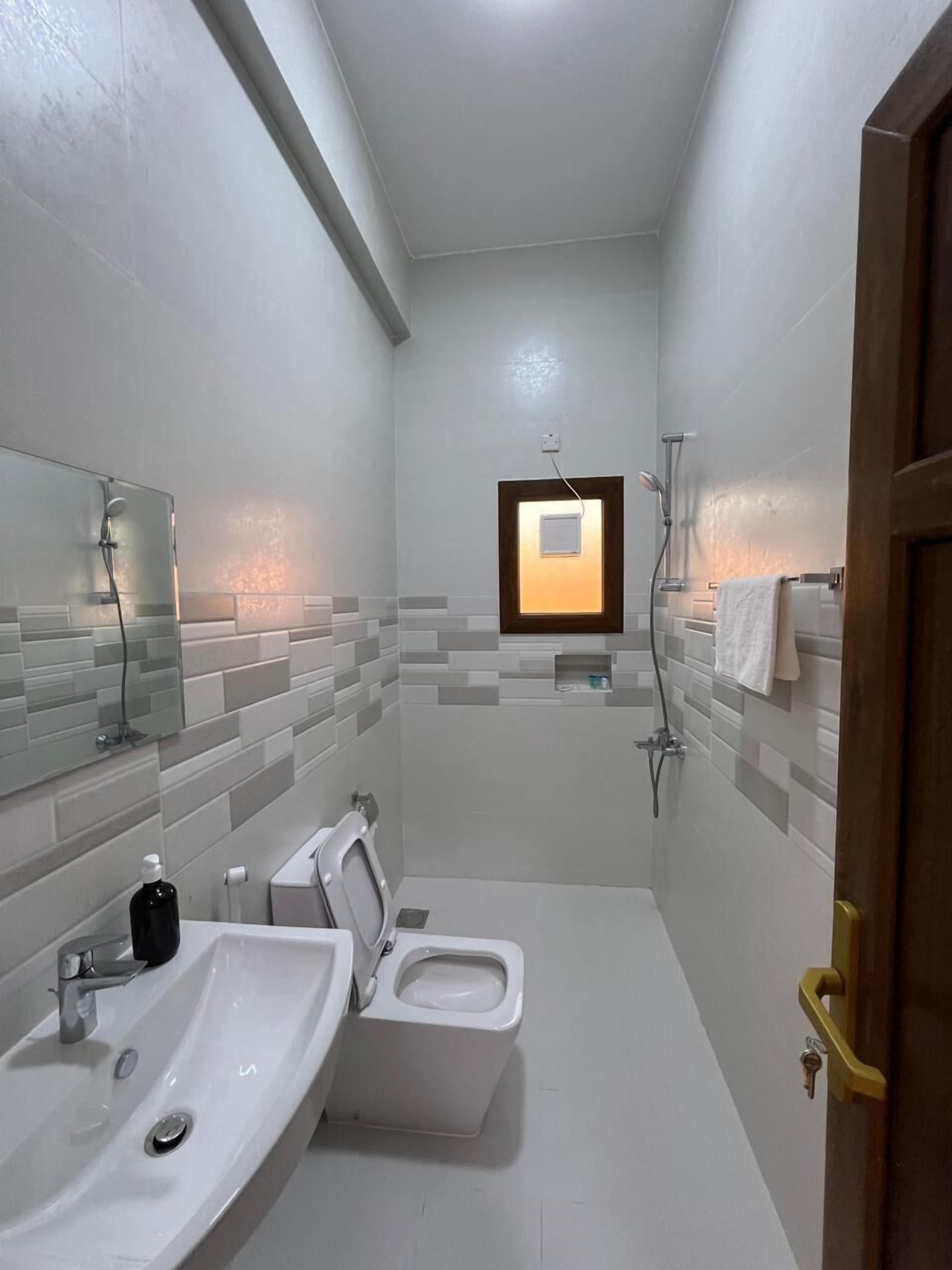 A compact bathroom with a sink, toilet, and shower.