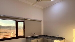 Una cocina con pileta integrada, ventilador de techo y ventana con vista a un paisaje desértico.