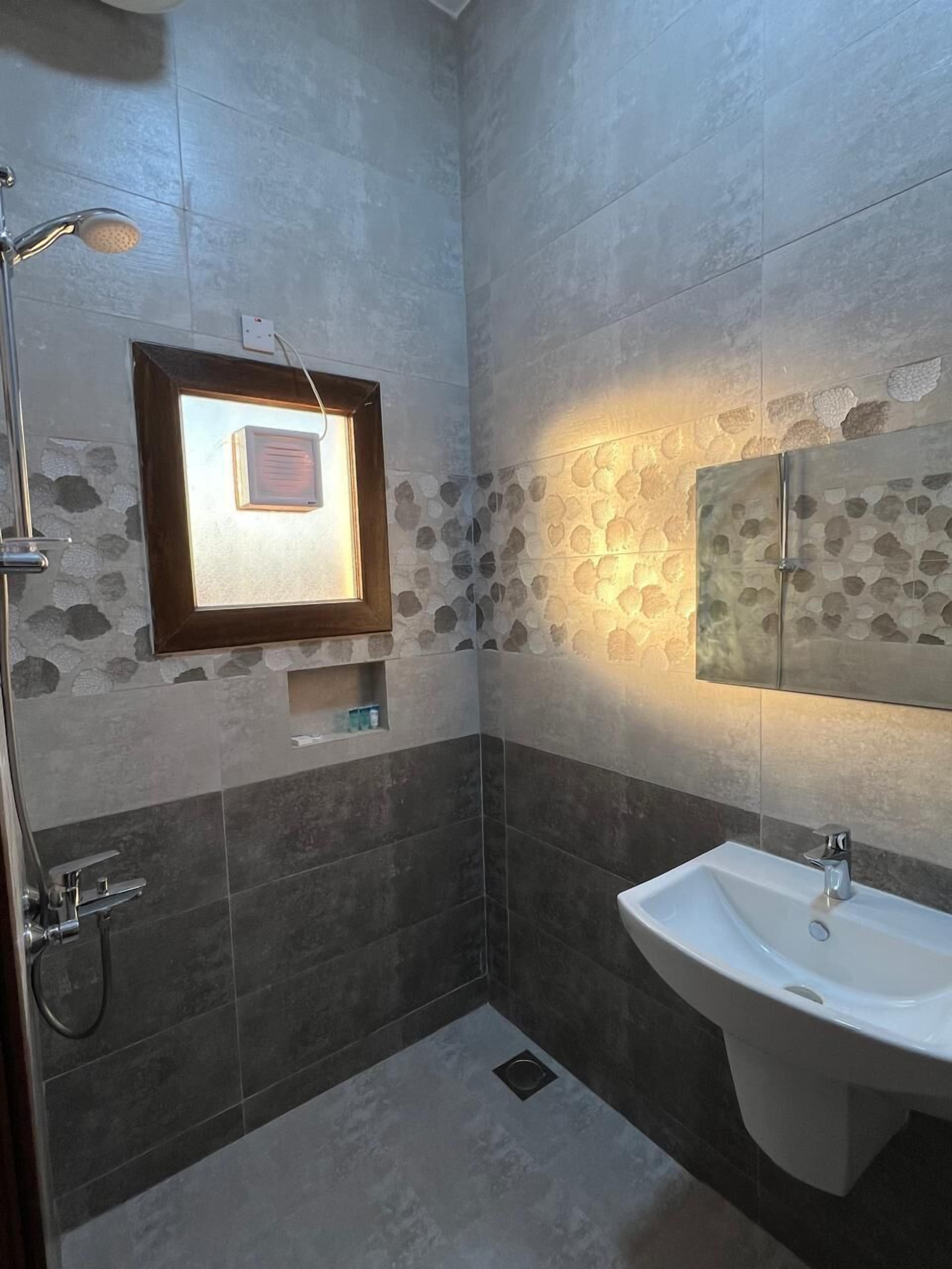 A bathroom with a shower, a sink, and a framed picture on the wall.