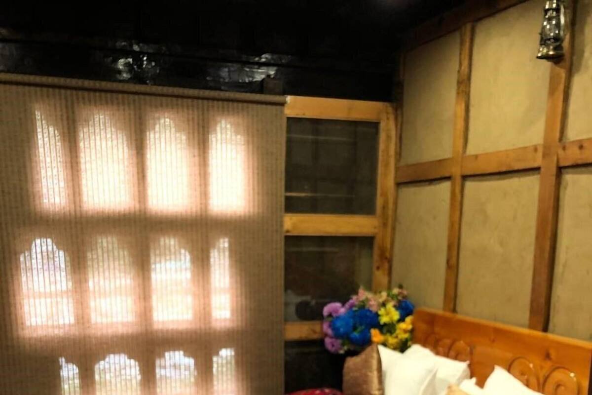 A bedroom with a wooden bed, a colorful rug, and a window with curtains.