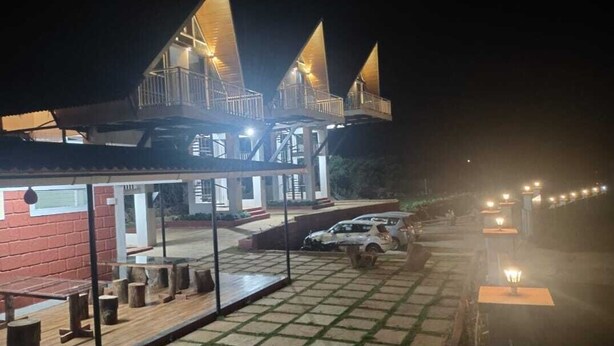 Un hotel con terraza en la azotea, zona de estar al aire libre y una fila de luces a lo largo del camino.