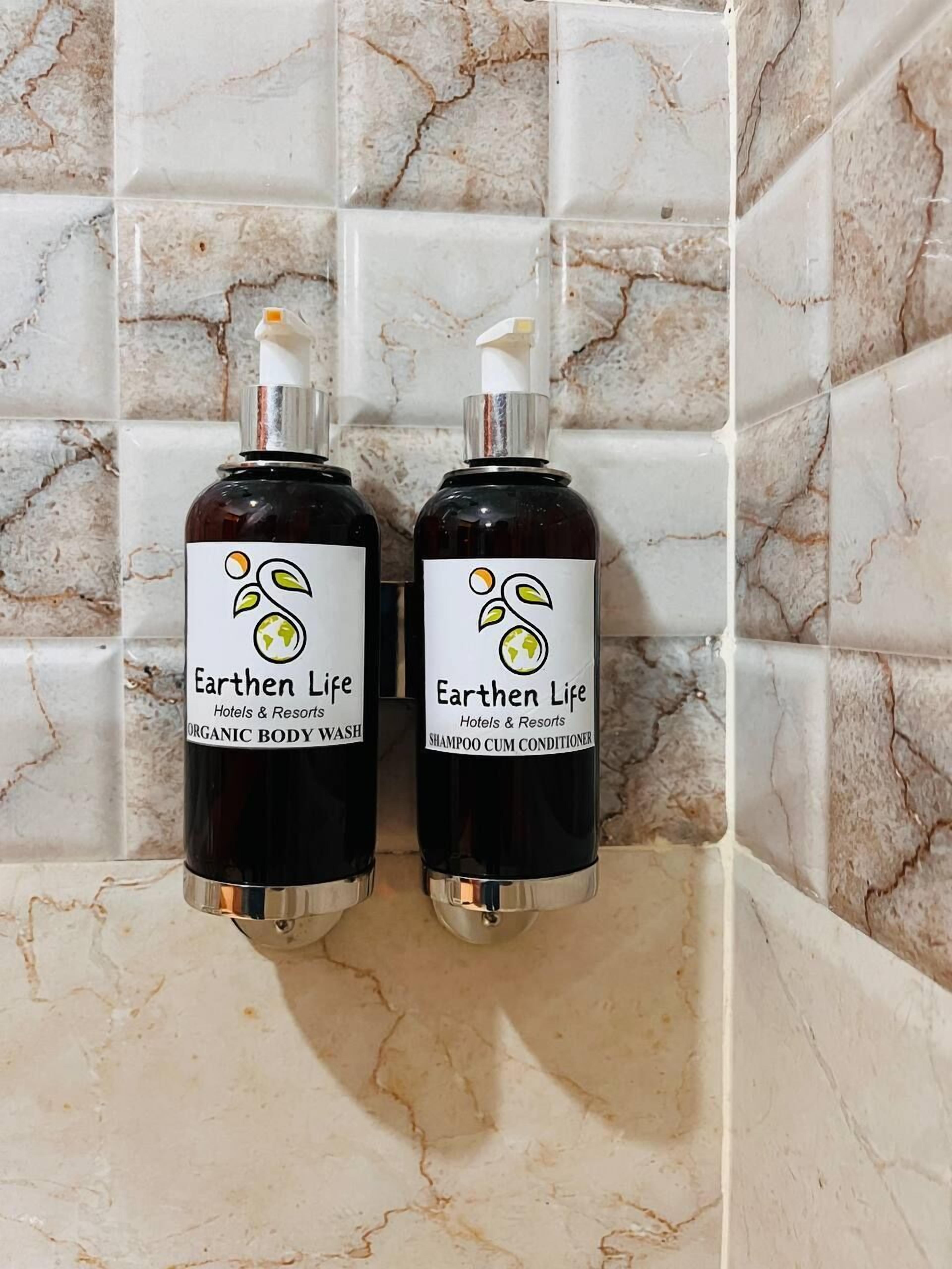 Deux bouteilles de gel douche et de shampoing-après-shampoing biologique de la marque Earthen Life, posées sur un comptoir en marbre.