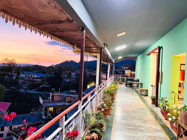 Un balcon offrant une vue sur un village et des montagnes au coucher du soleil.