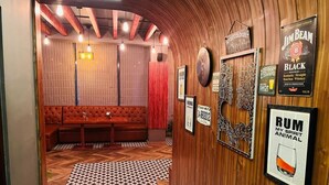 A hallway with a patterned floor, wooden walls, and a seating area with a red curtain. - Hotel Palampur Life (Palampur)
